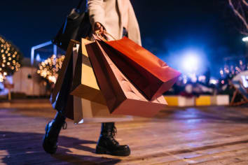 shopper in the early morning darkness holding shopping bags