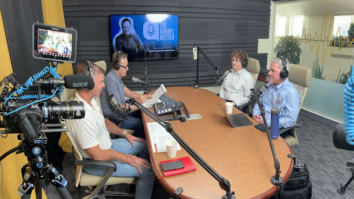 Podcast host and interviewers sitting at table in podcast studio with headsets and microphones