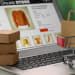 Mini shopping bag, boxes and cart on laptop, closeup. Online store
