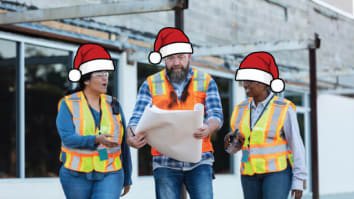 Three people in Santa hats and high vis vests looking at blueprints