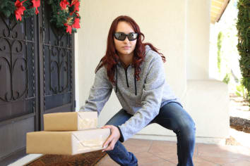 Female in sunglasses removing package from a porch