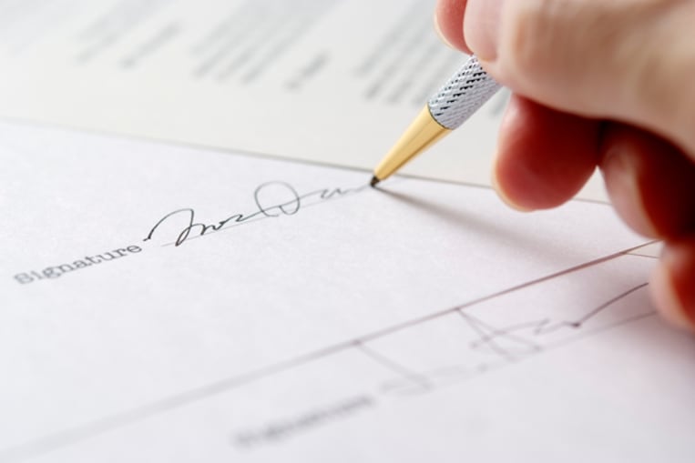 Close-up of signing a contract with shallow depth of field.