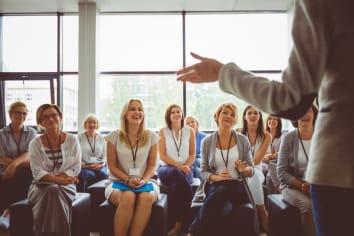 Group of business women smiling and listening to the speaker during seminar. Women attending a skill development training in conference hall.