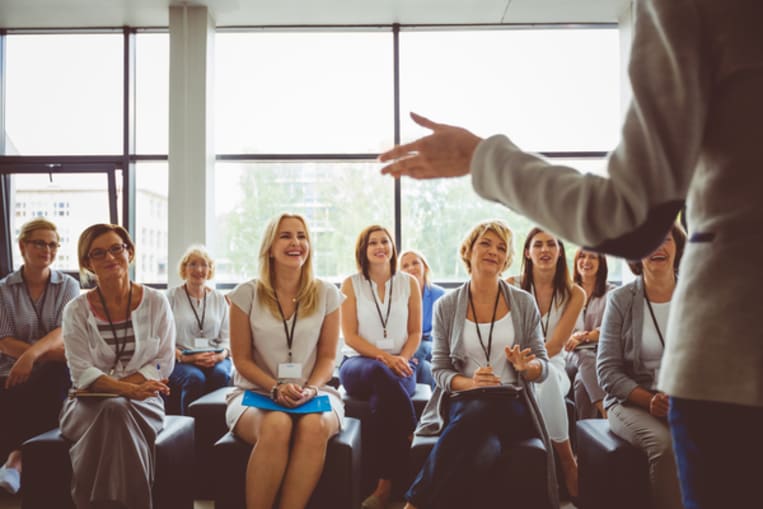 Group of business women smiling and listening to the speaker during seminar. Women attending a skill development training in conference hall.