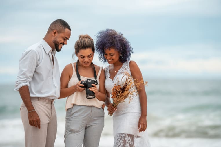 Photographer shows wedding photos to the bride and groom - stock photo