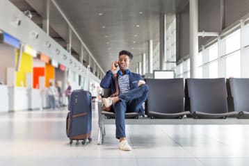 young african american man sitting in airport on the phone