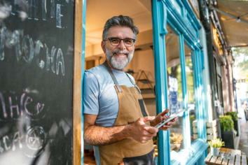 Cheerful male barista opening his coffee shop in the morning
