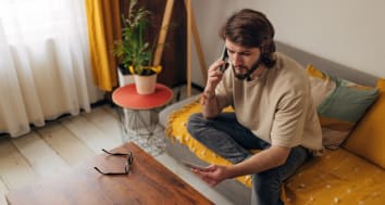Man in room looking at card while on his phone