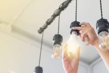 LED light Power saving concept. Man changing compact-fluorescent (CFL) bulbs with new  bulb.