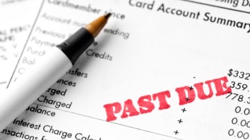 Close-up view of a pen resting on top of a credit card bill marked "past due."