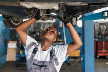 african american auto mechanic woman working on car