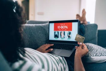 Unrecognizable Woman enjoying big sale and shopping online with credit card and laptop at home