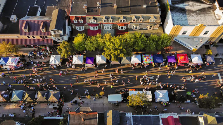 Top-down view of vendor tents and attendees at a street festival.