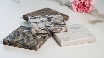 A close-up image of four stone countertop samples for a kitchen or bathroom remodel.