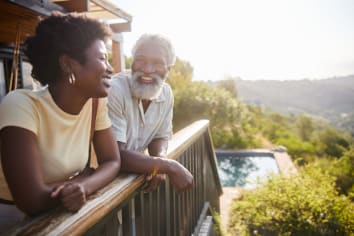 Laughing couple standing on the balcony of their luxury vacation rental