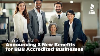 Group of business people around a laptop smiling at the camera