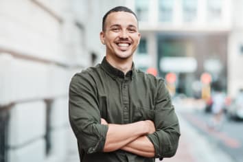 man smiling standing on sidewalk in city