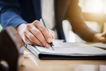 person in suit looking at documents at desk