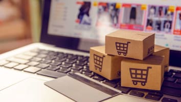 cardboard boxes with shopping cart icons sitting on laptop on online shopping screen with credit card