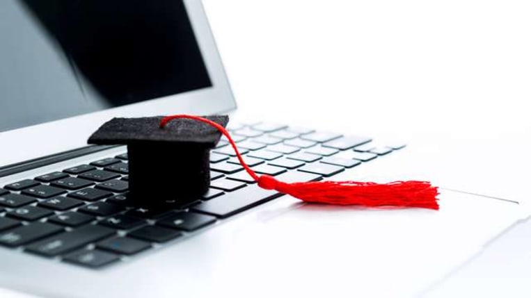 graduation cap sitting on laptop