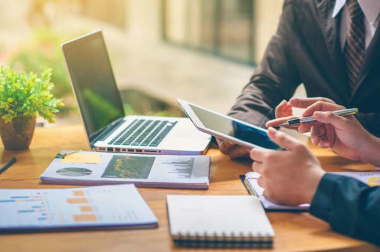 business people sitting at desk with laptop and smartphone