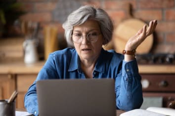 older adult looking at computer with frustrated look