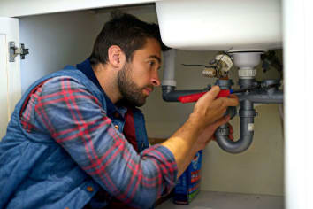 plumber inspecting pipes under sink