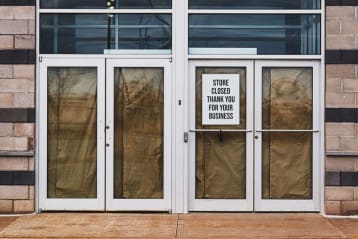 storefront with paper over the doors and windows with a sign saying store is closed