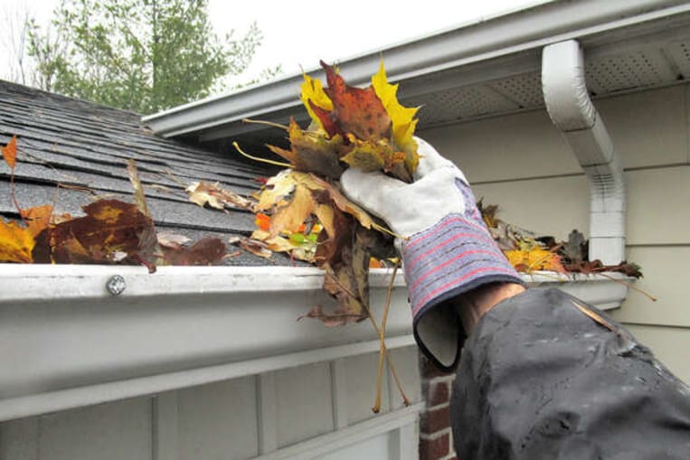 man cleaning gutter fall leaves on roof