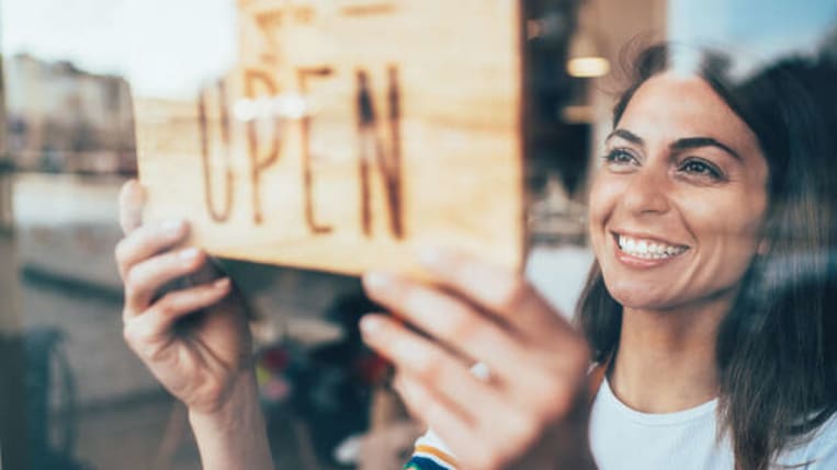 Woman putting open sign on door.