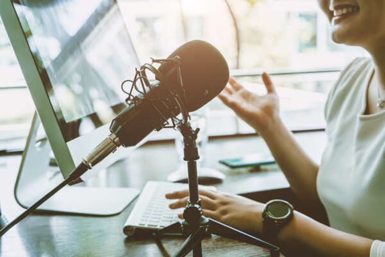 woman podcaster smiling and speaking into microphone