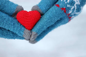 person with blue gloves holding red heart