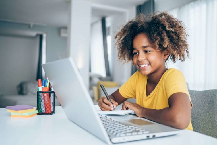 young african american child doing schoolwork on laptop