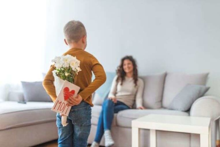 little boy surprising mother with flowers on mother's day