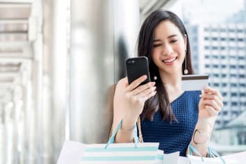 happy woman shopping on phone with credit card