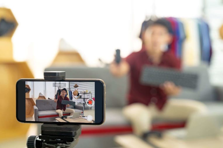social influencer filming video on couch with tripod and smart phone