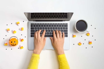 Typing on laptop with coffee and candy corn