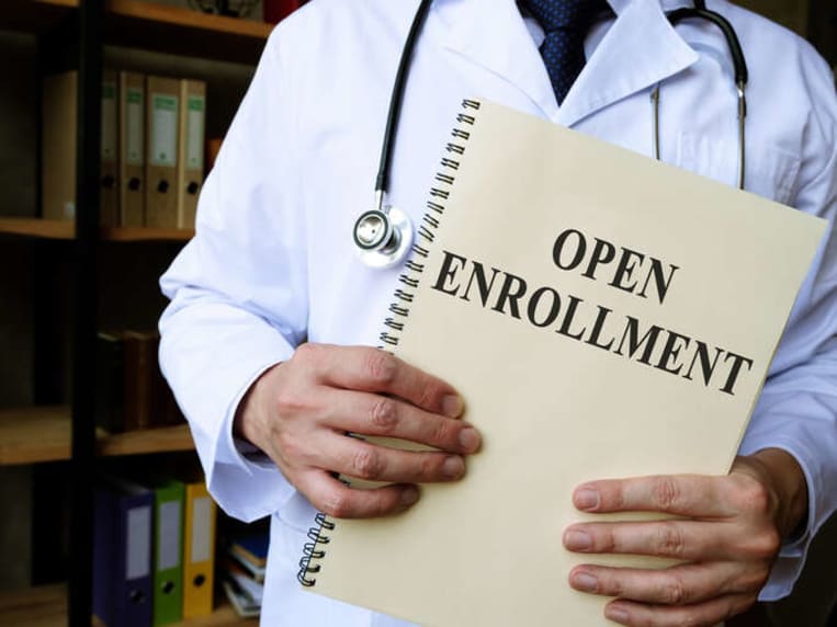 doctor holding a paper that says open enrollment