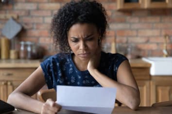 woman sitting at table looking at mail